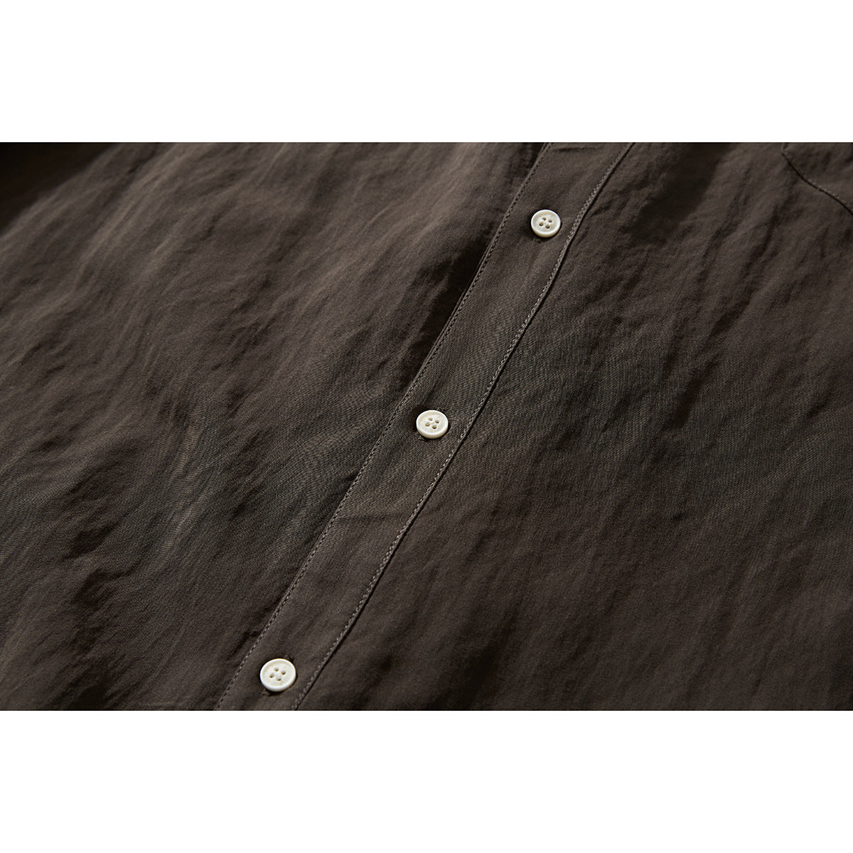 Close-up of the dark brown shirt's front placket with three white buttons and textured fabric.