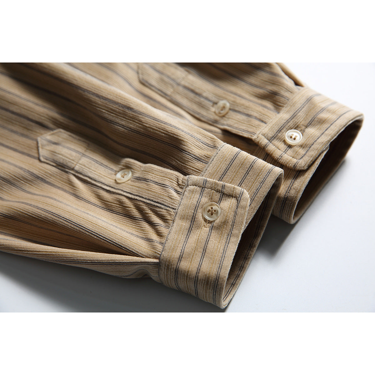Close-up of the buttoned cuffs and sleeves of a beige shirt with fine vertical stripes.