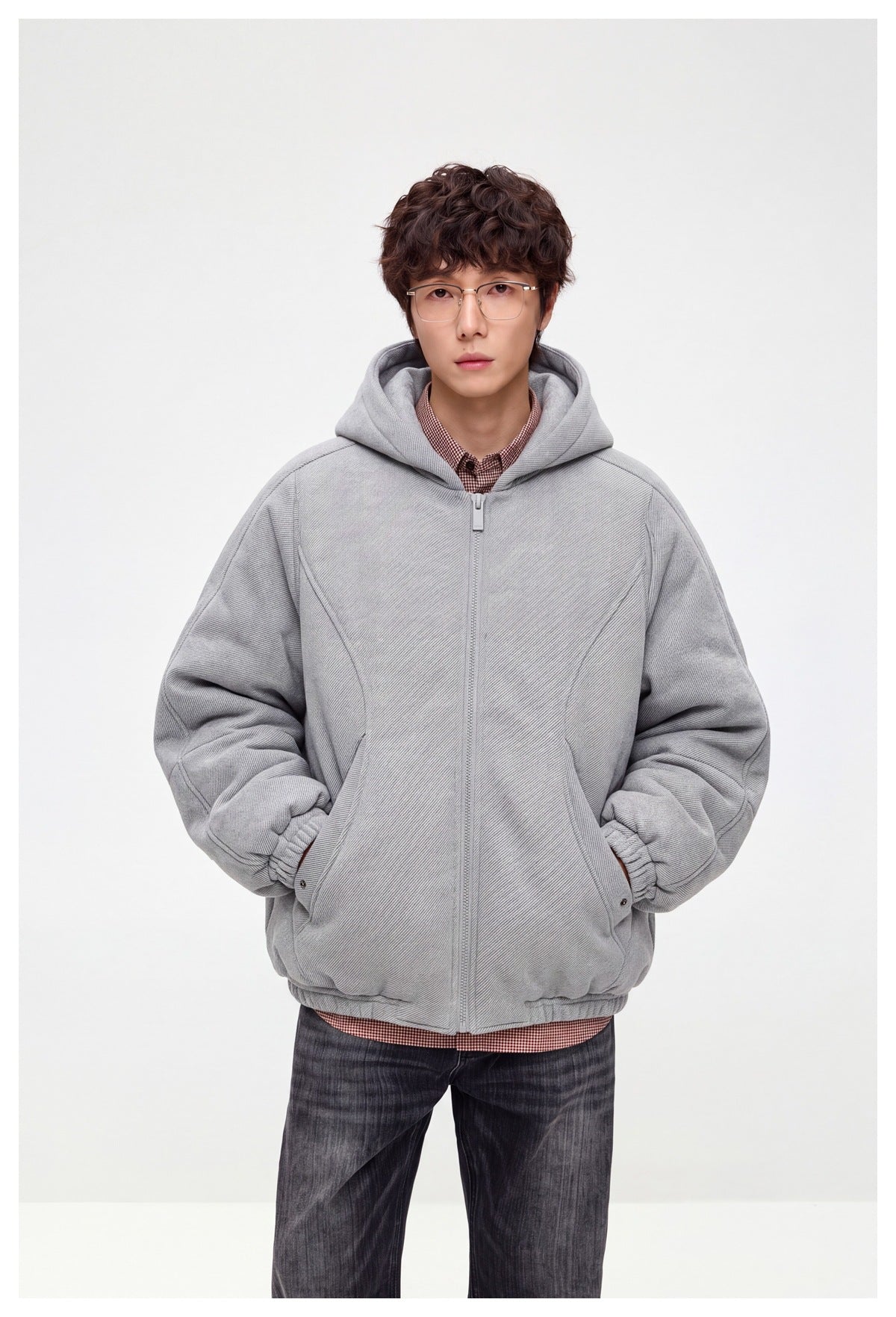 Front view of a model wearing a light gray hooded zip-up jacket with curved pockets and gathered cuffs.
