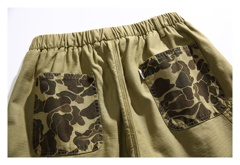 Rear view of khaki shorts with an elastic waistband and two brown camouflage-patterned pockets.