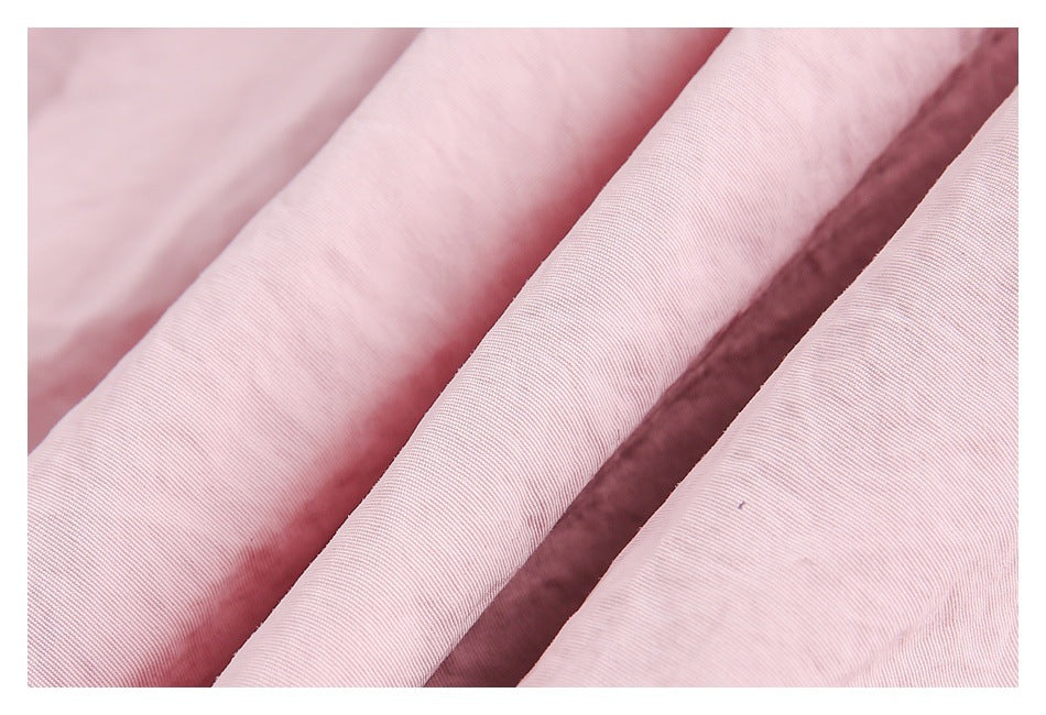 Close-up of pale pink fabric showing its fine woven texture and soft folds.