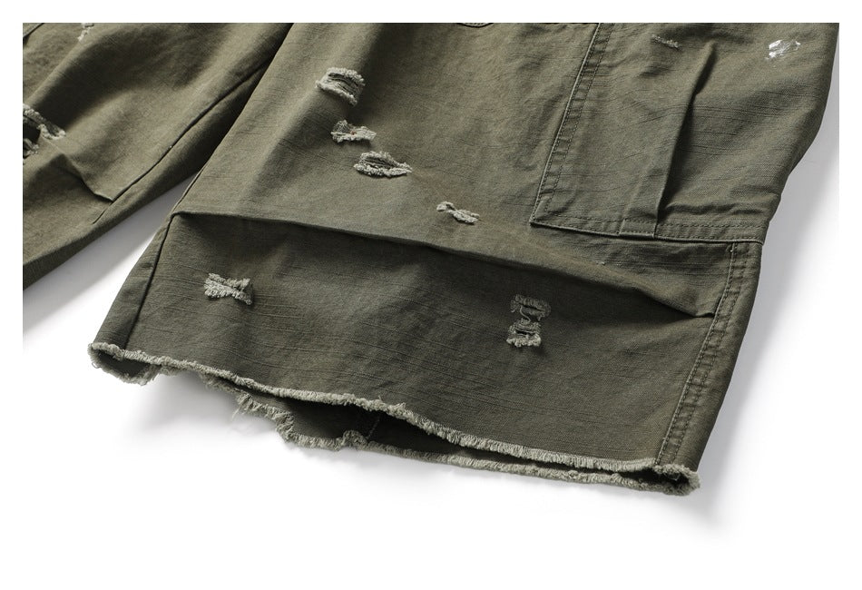 Close-up of olive cargo trousers showing a frayed hem, distressed spots, and panel stitching.