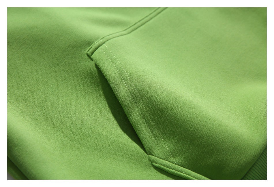 Close-up of the green hoodie’s kangaroo pocket seam and stitching.