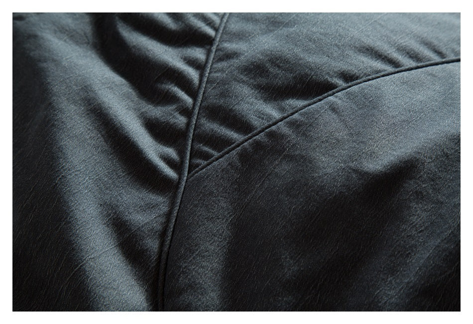 Close-up of curved stitched seams on dark charcoal jacket fabric.