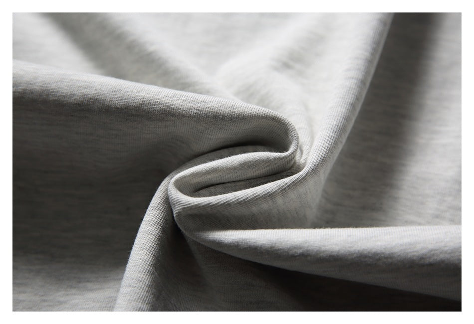 Close-up of light gray knit fabric draped into soft folds, showing a fine ribbed texture.