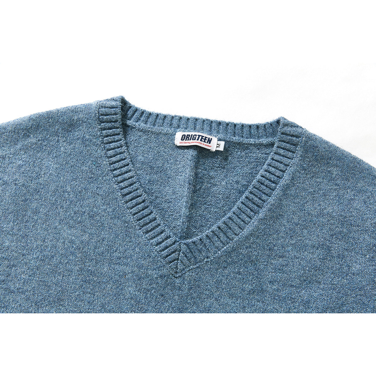 Close-up of a blue knit V-neck vest showing its ribbed neckline and sewn-in neck label.