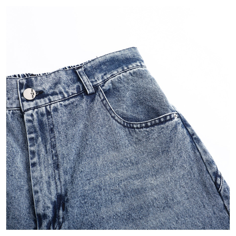 Close-up of the waistband, belt loop, and front pocket on blue acid-wash jeans.