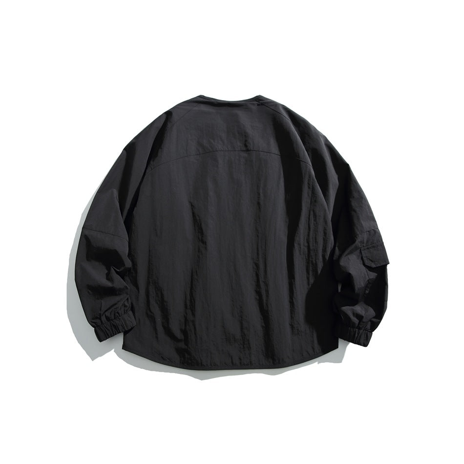 Back view of a black jacket laid flat, with a curved yoke seam, roomy sleeves, and gathered cuffs.