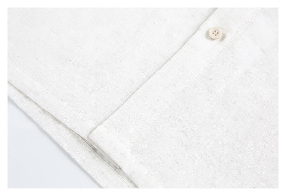 Close-up of an off-white garment's button placket with a small matching button and fine slubbed texture.