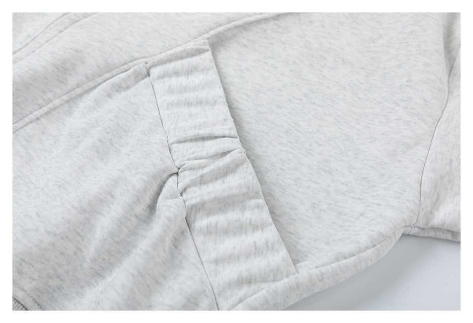 Close-up of stitched panel seams on a light heather-gray hoodie.