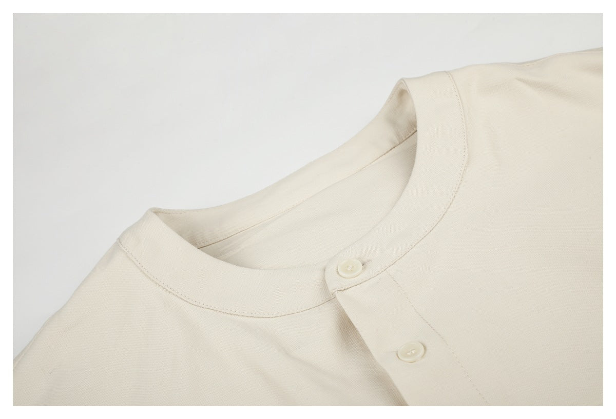 Close-up of the off-white shirt's band collar and upper button placket.