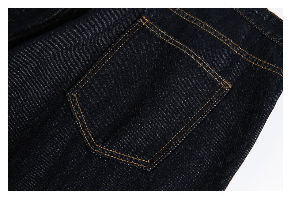 Close-up of a patch pocket on dark indigo jeans with golden double stitching.