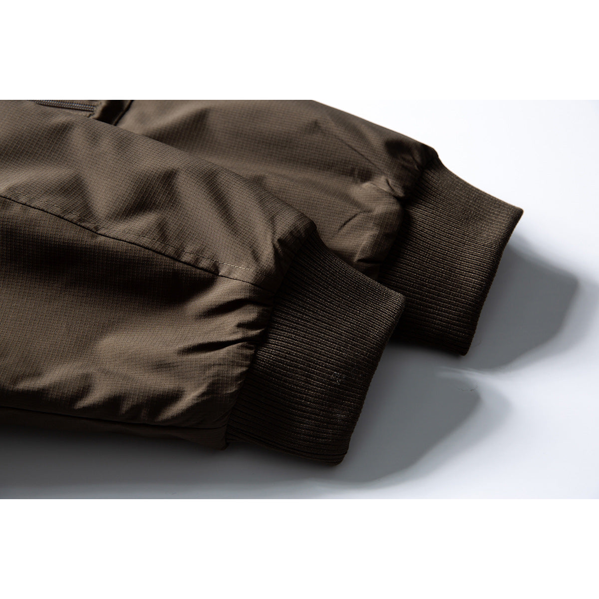 Close-up of the dark brown jacket's ribbed cuffs and sleeve fabric.