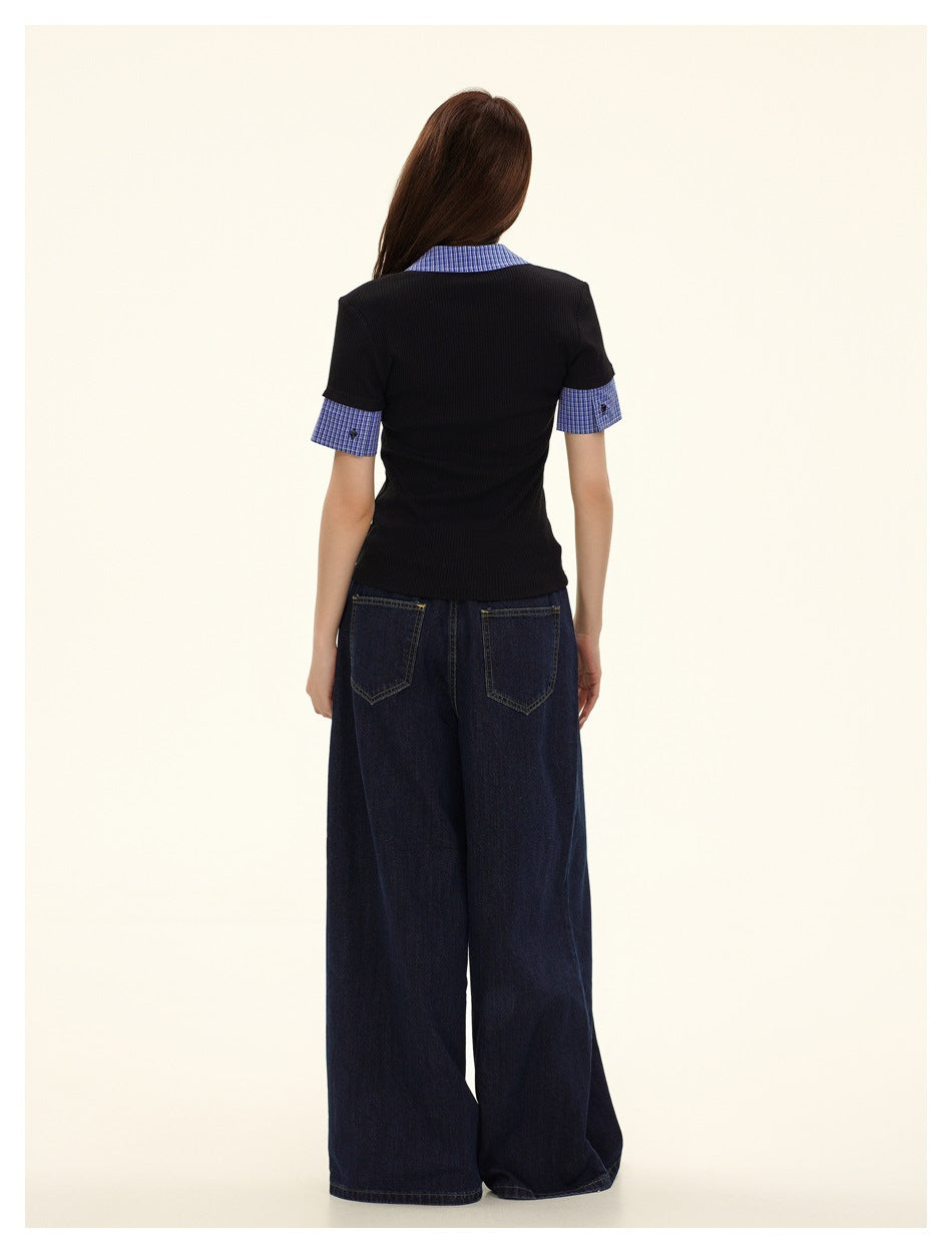 Back view of a model wearing a black polo with blue check accents and dark wide-leg jeans.