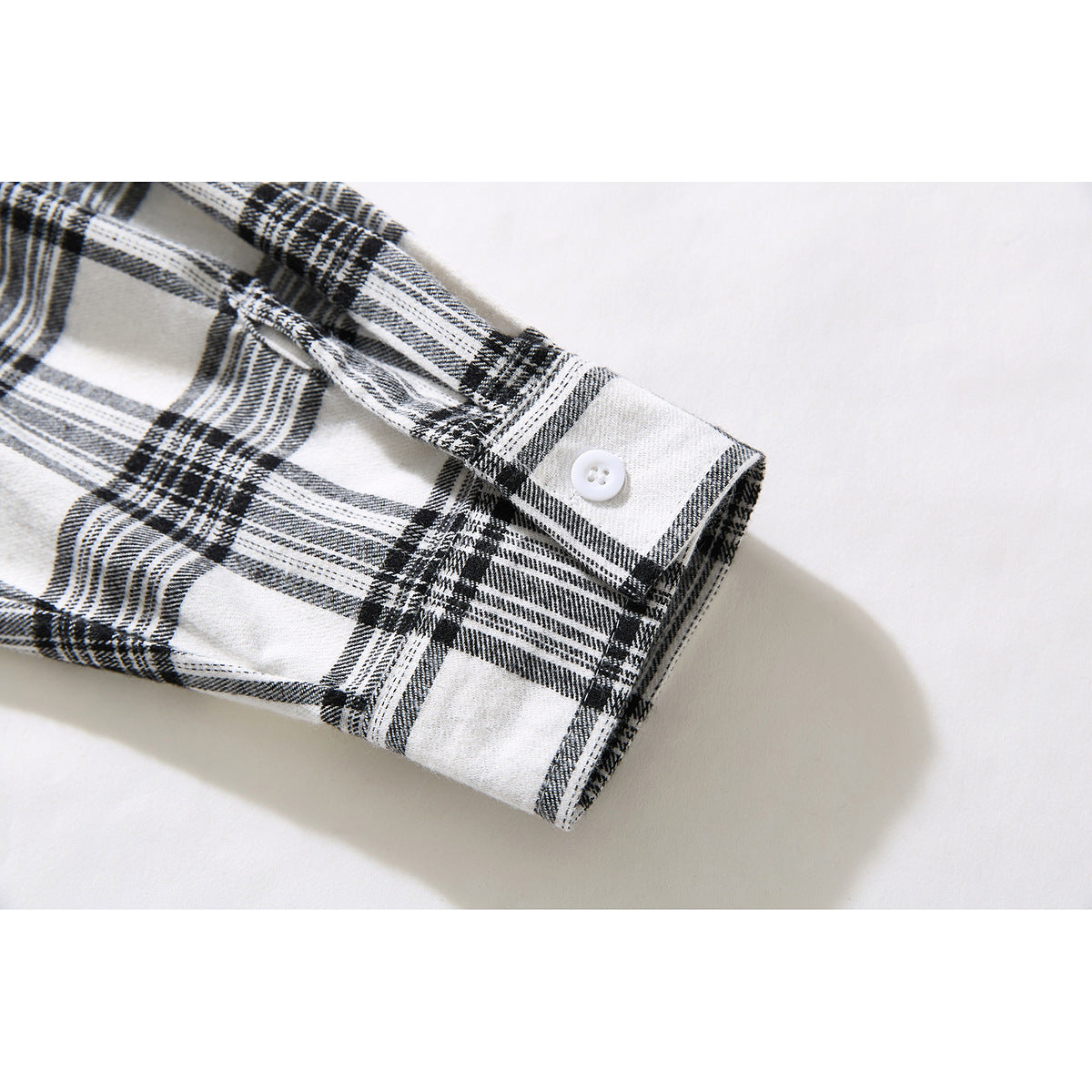 Close-up of a black-and-white plaid shirt sleeve cuff with a white button.
