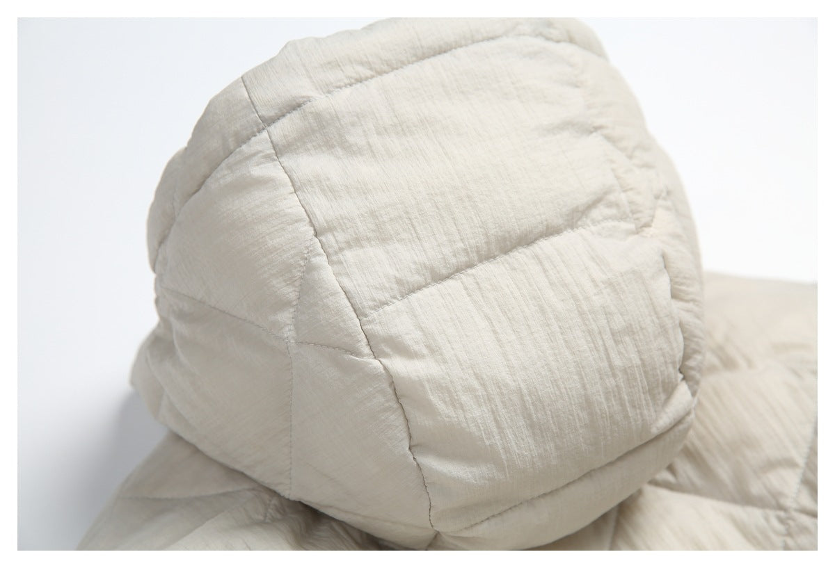 Close-up of a padded, rounded section of the cream quilted jacket with stitched panels.