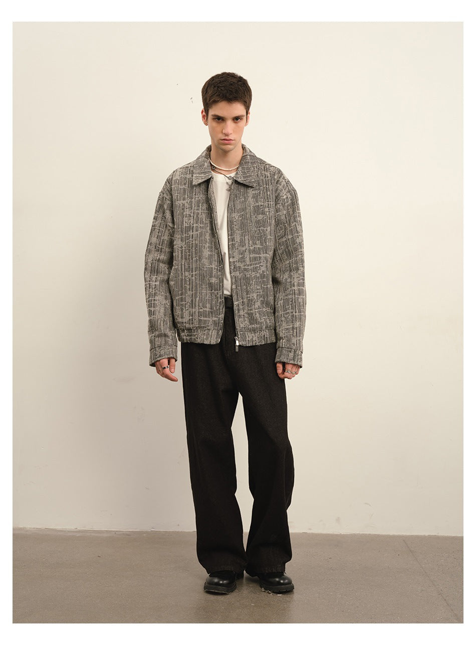 Front view of a model wearing a gray abstract-patterned zip-front jacket and black wide-leg pants.