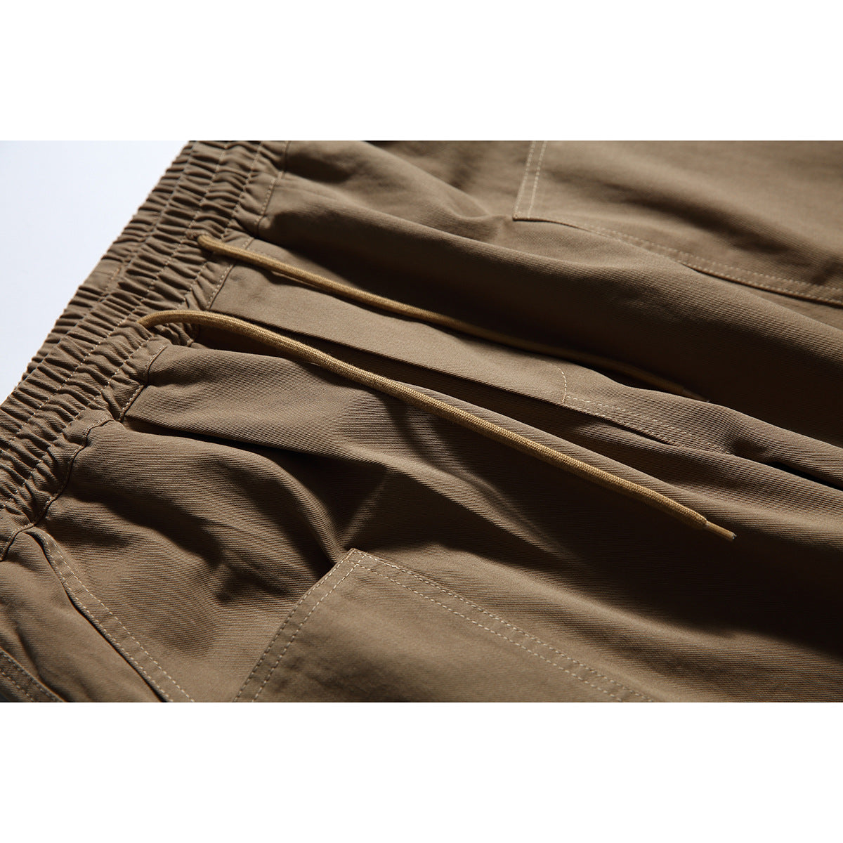 Close-up of brown pants with a gathered elastic waist and long drawcords.