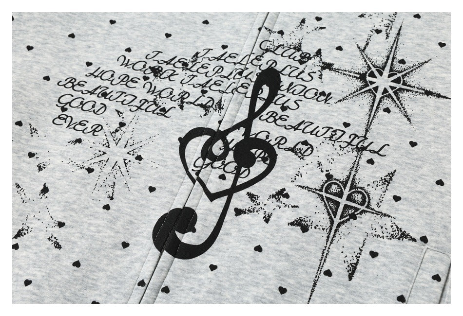 Close-up of a gray garment printed with black hearts, decorative English lettering, and treble-clef and star motifs.