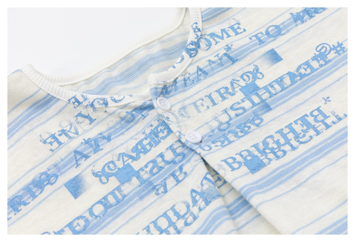 Close-up of distressed blue lettering and stripes around the top's white two-button placket.