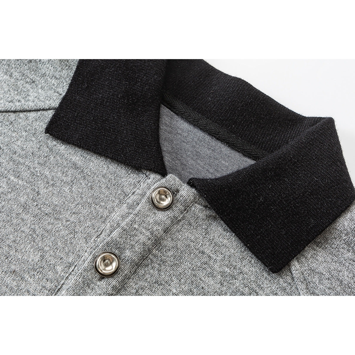 Close-up of a gray pullover's black collar and two metallic buttons.