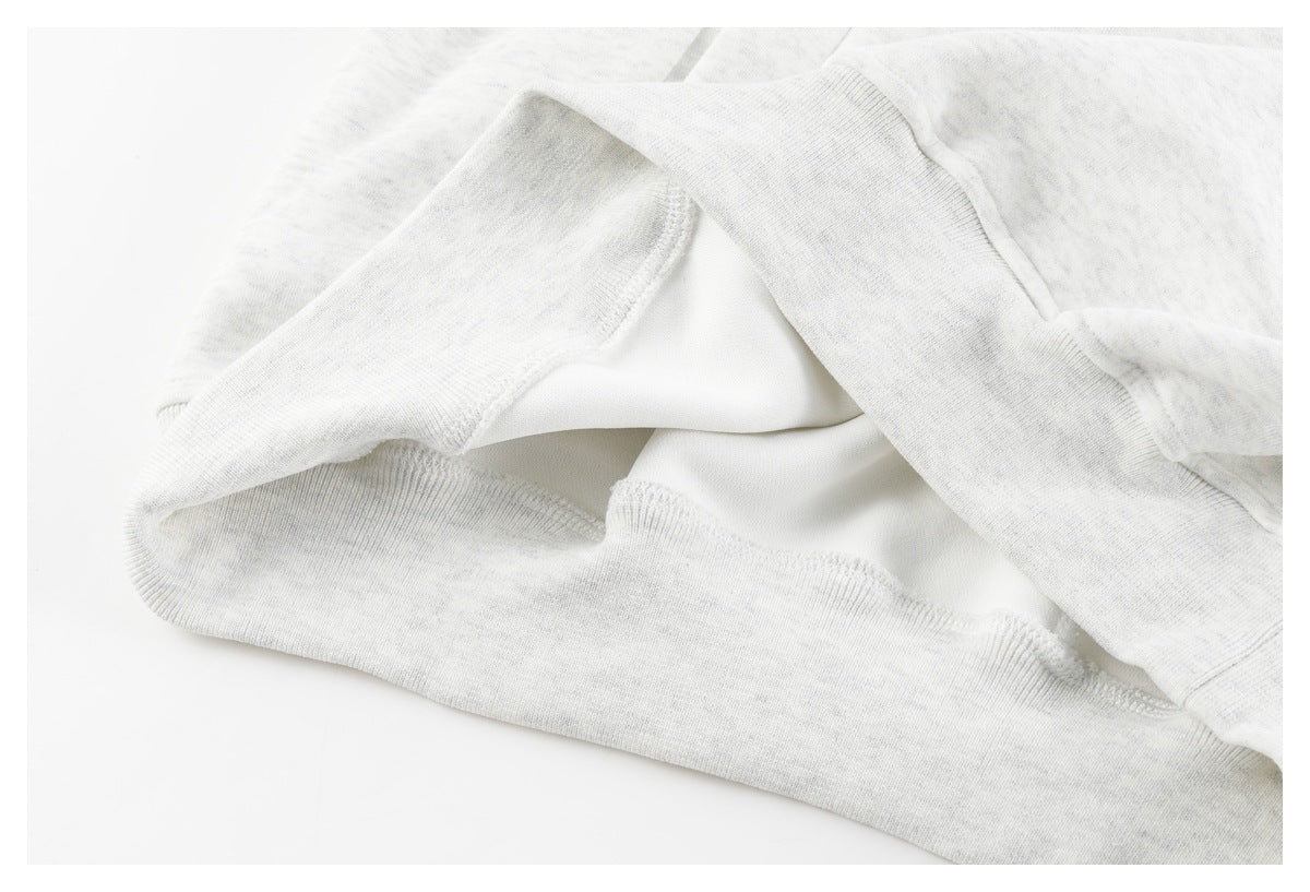 Close-up of the inside seams and hem of a light gray sweatshirt.