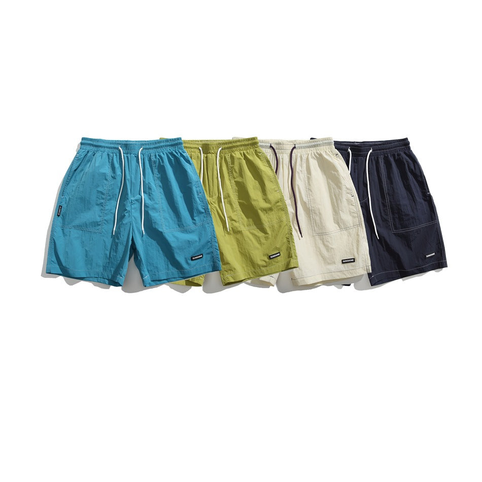 Four pairs of front-facing drawstring shorts in teal, lime green, cream and navy.