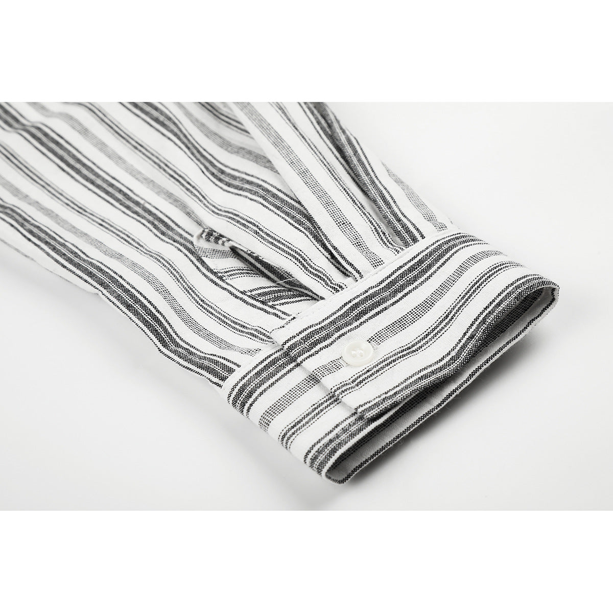 Close-up of a white shirt sleeve with black stripes, buttoned cuff and sleeve placket.