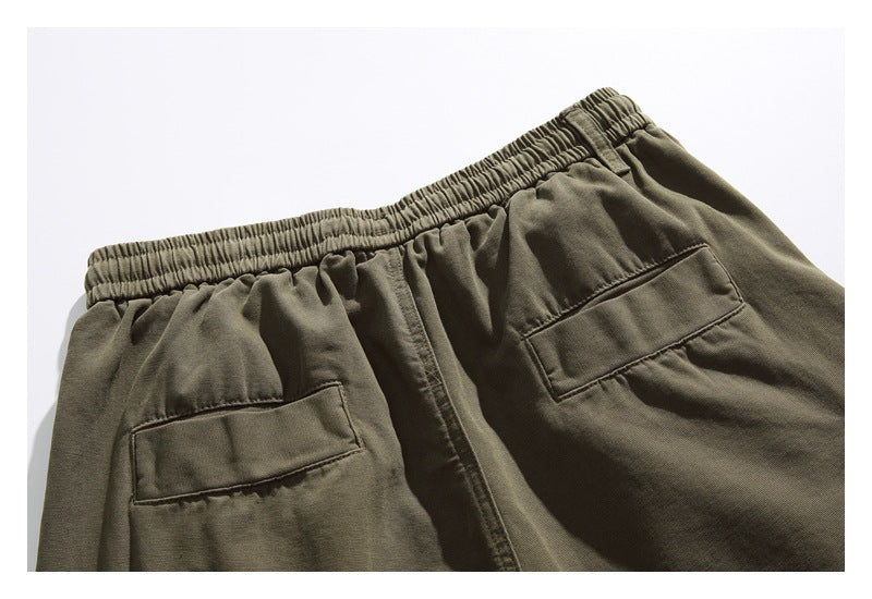 Back view of olive shorts laid flat, with an elastic waistband and two rectangular pockets.