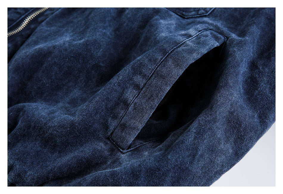 Close-up of an angled side-entry pocket on a dark blue washed jacket.