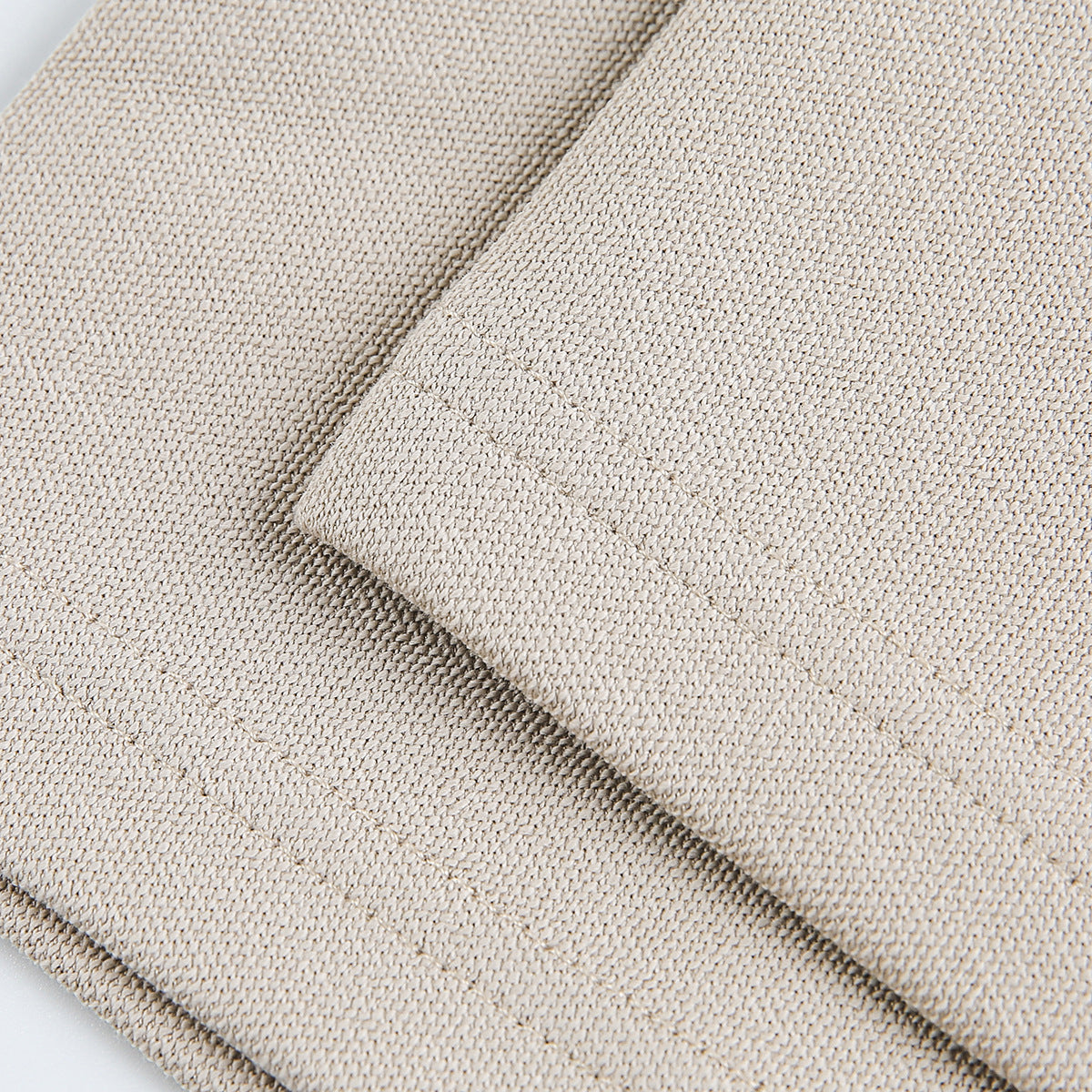 Close-up of beige fabric with a folded edge and visible knit texture.