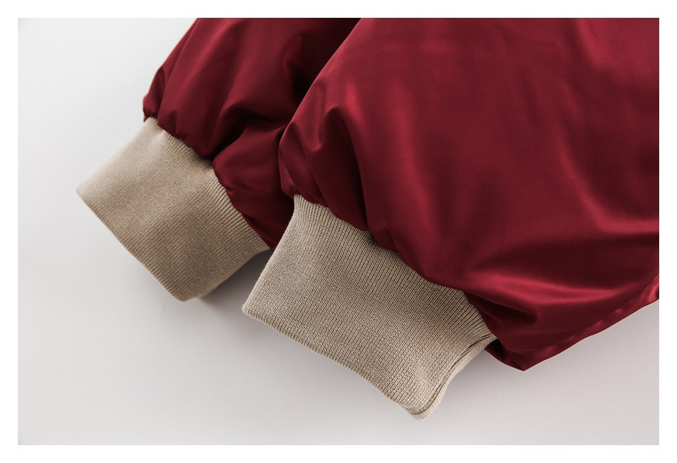 Close-up of burgundy jacket sleeves ending in wide beige ribbed cuffs.