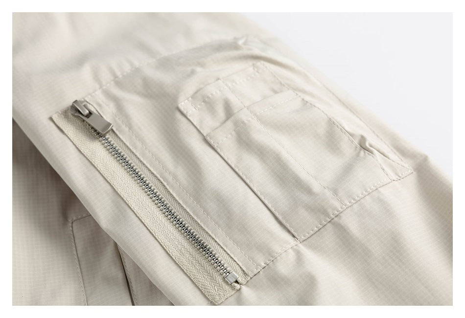 Close-up of a zippered pocket and stitched flap pocket on the cream jacket.