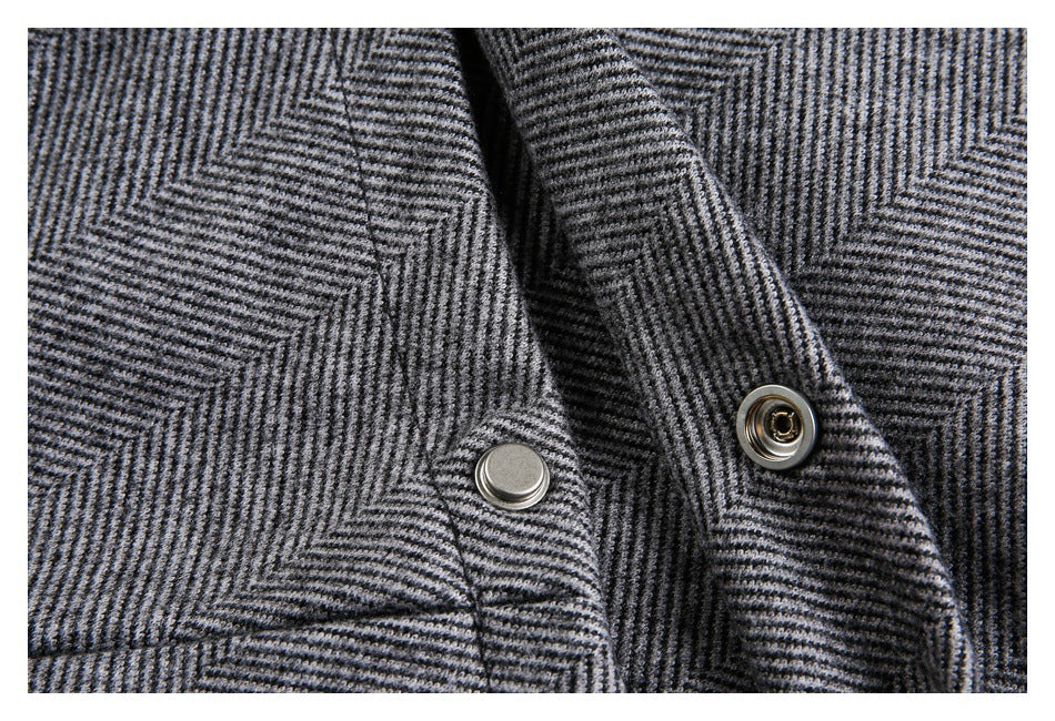 Close-up of two metal snap fasteners on gray herringbone fabric.