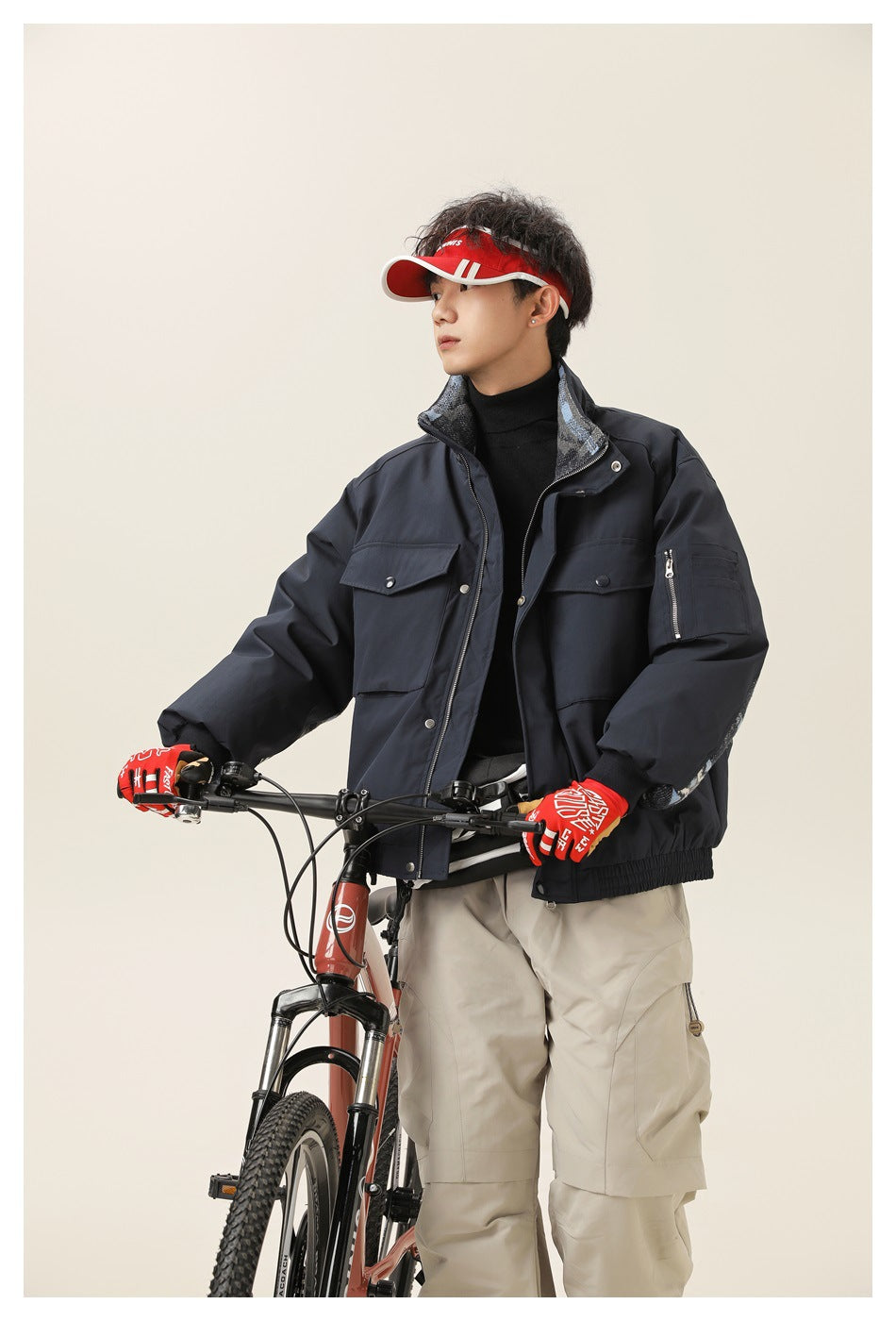 Model wearing a navy utility jacket with a high collar, flap pockets, a sleeve zip pocket and patterned lining.