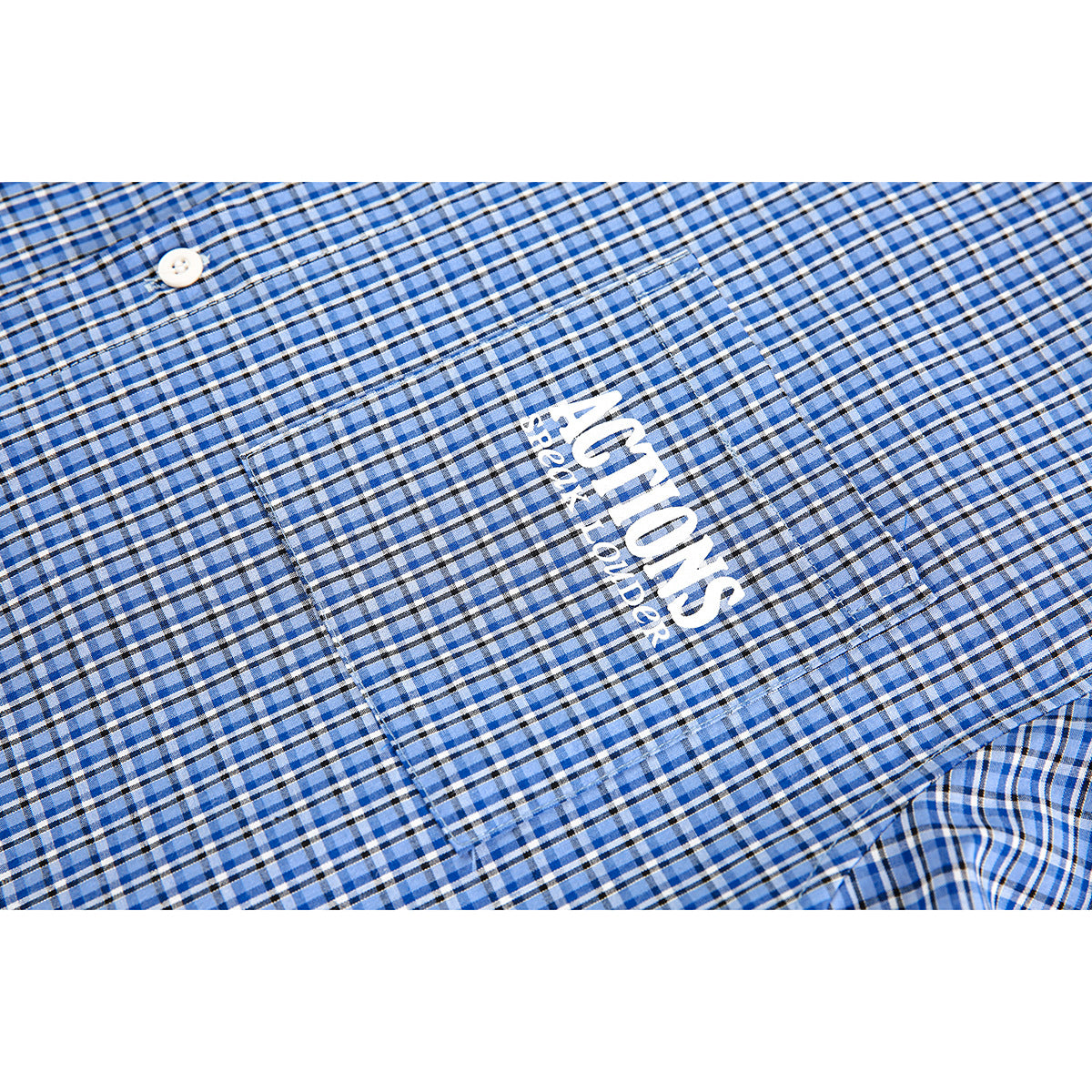 Close-up of a blue plaid shirt pocket with white printed lettering and a button.