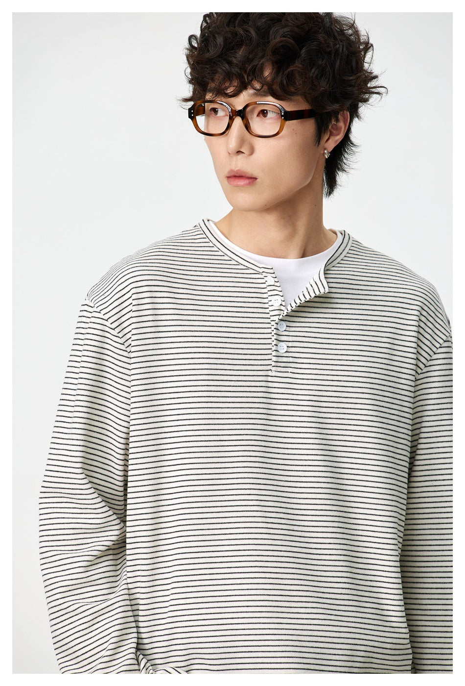 Close view of an ivory thin-striped henley with a short button placket, worn by a model.
