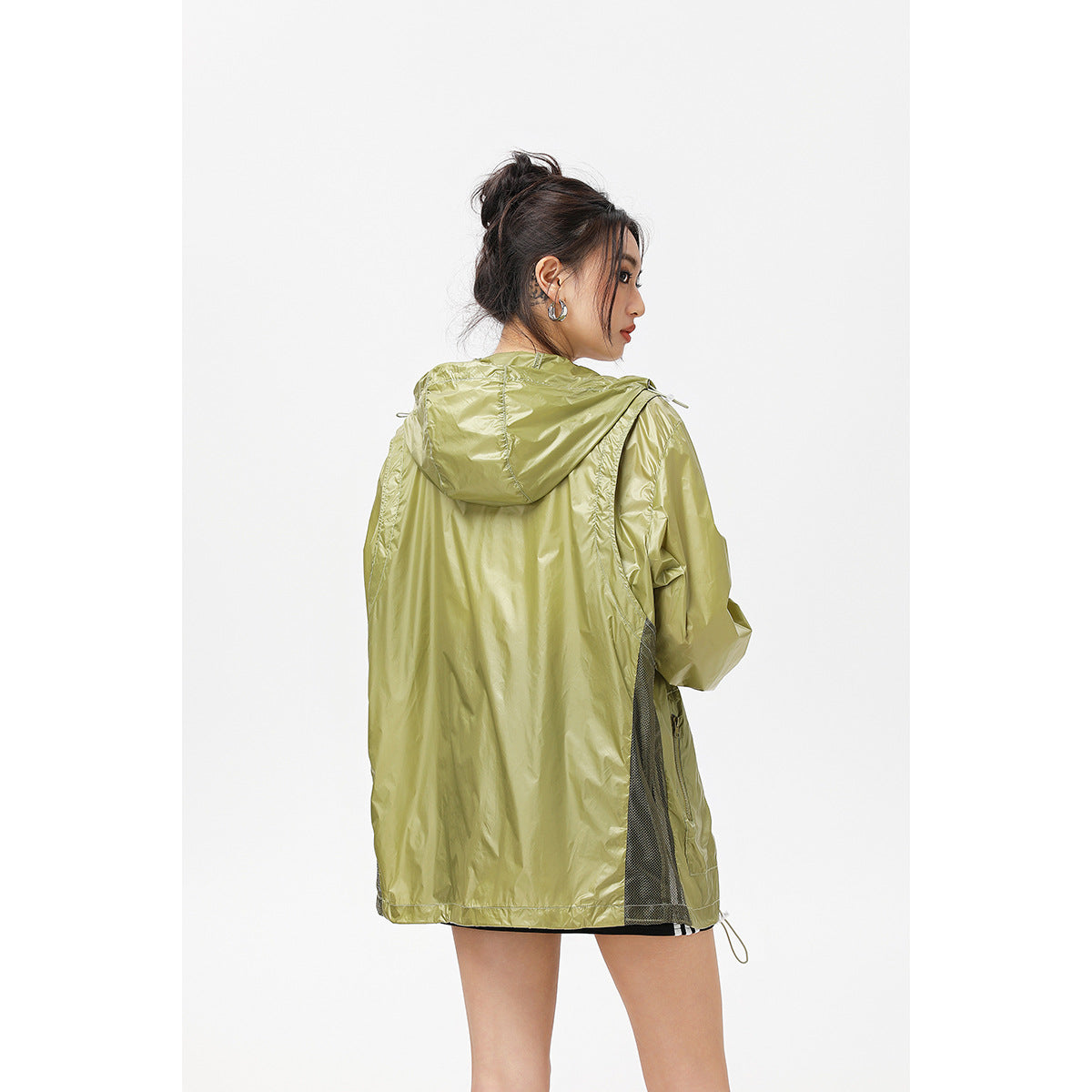 Rear view of a model wearing an olive-green hooded jacket with mesh side panels.