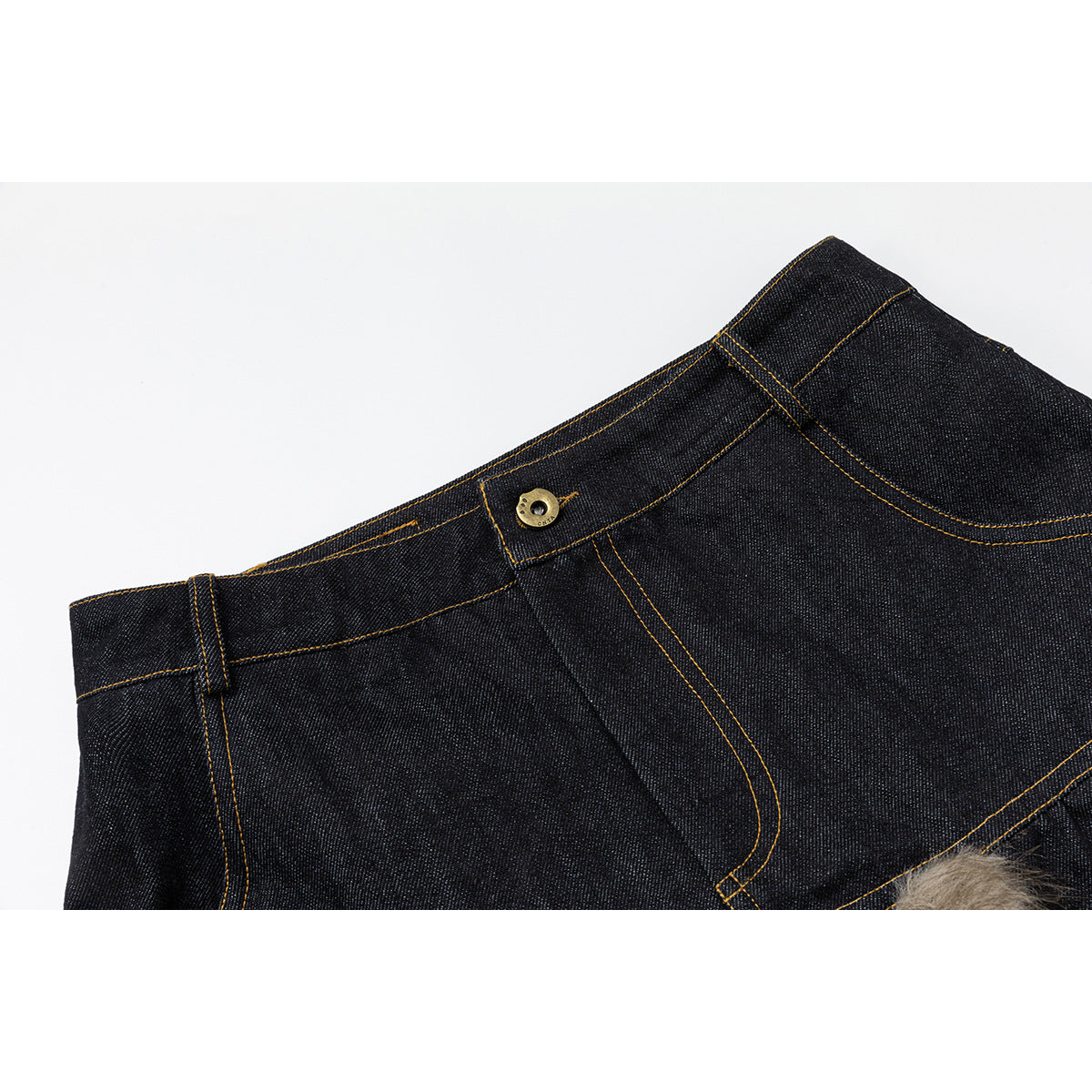 Close-up of dark indigo jeans with ochre stitching, waistband button, belt loop and fly seam.