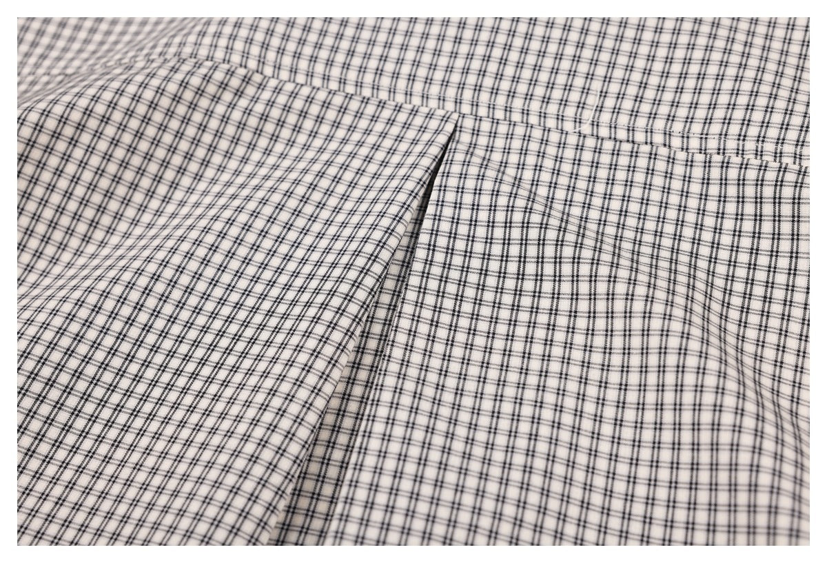 Close-up of the checked shirt's back yoke seam and fabric pleat.