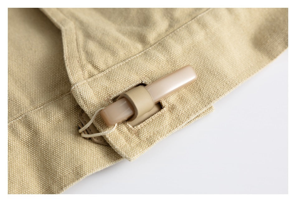 Close-up of a tan plastic toggle threaded through a beige woven fabric loop.