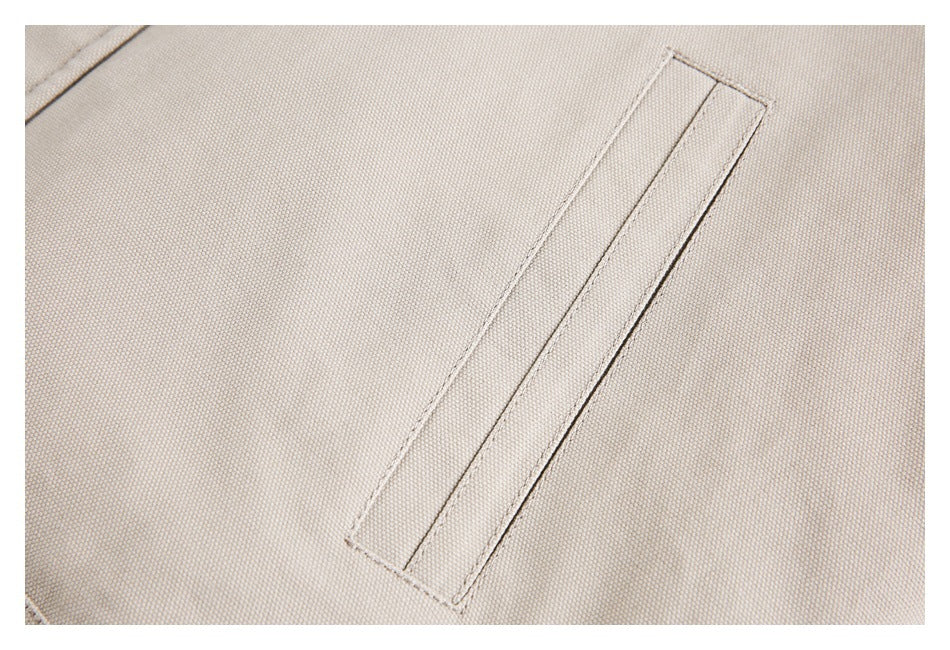 Close-up of a narrow welt pocket on beige woven fabric.