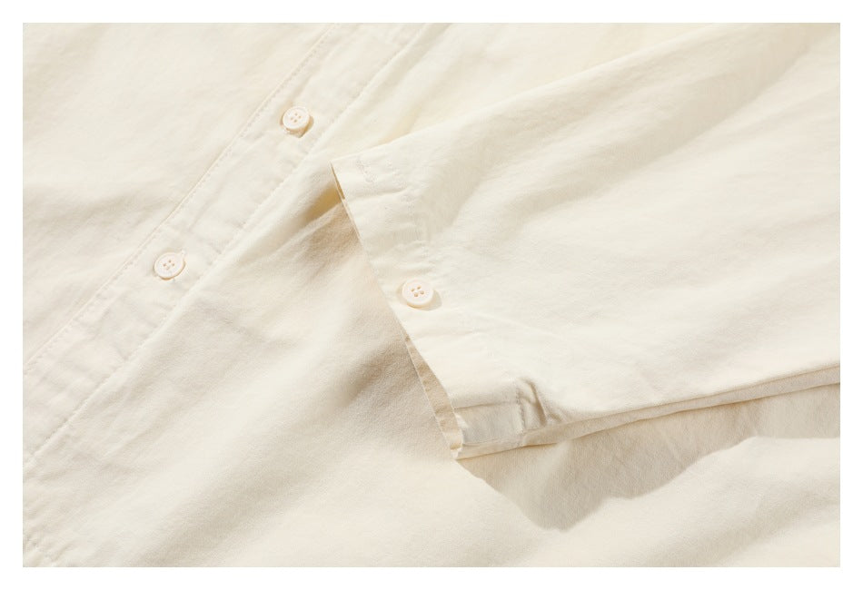 Close-up of the buttoned cuff and placket on an off-white long-sleeve garment.