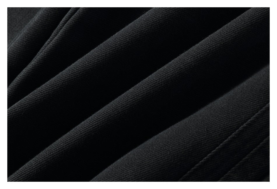 Extreme close-up of the textured black trouser fabric and folds.