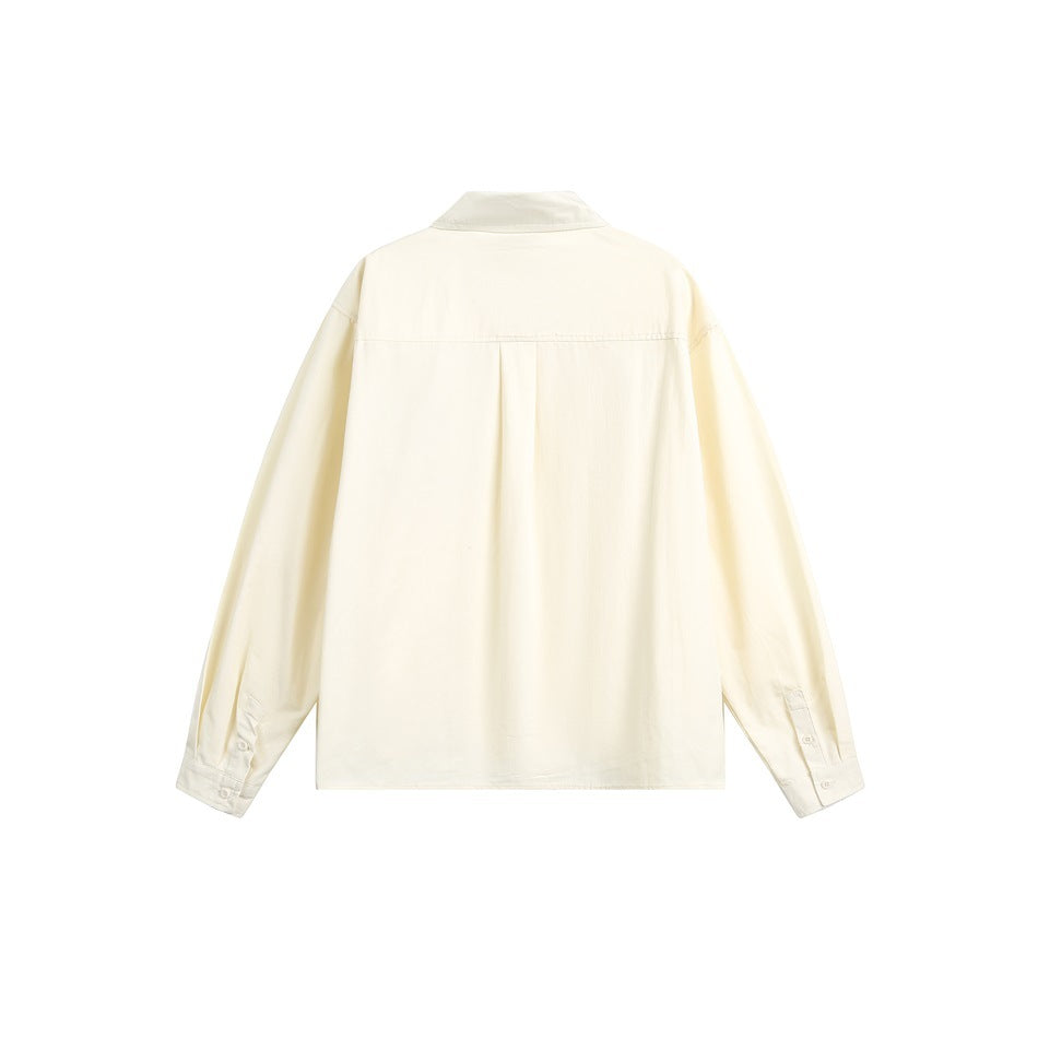 Back view of a pale cream long-sleeve button-up shirt with a yoke seam and center pleat.