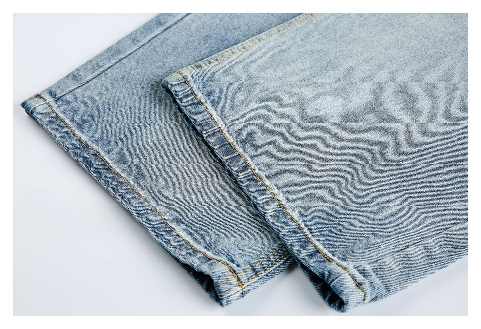 Close-up of the double-stitched hems on light-wash denim jeans.