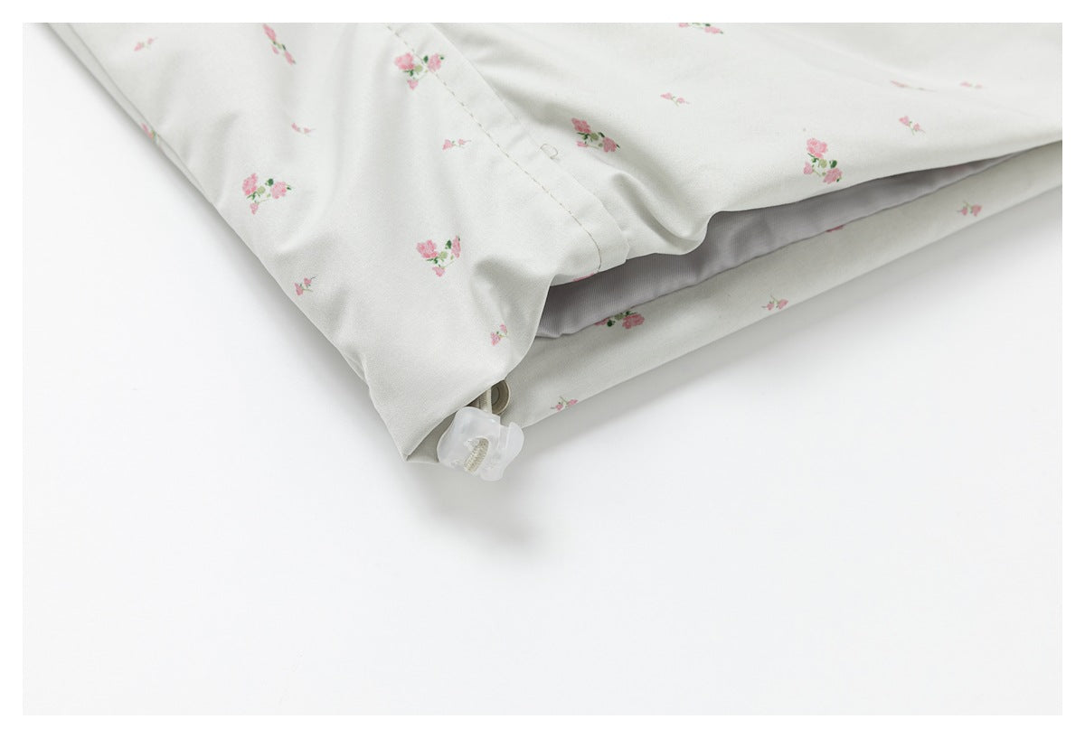 Close-up of the floral jacket hem and a small drawcord toggle.