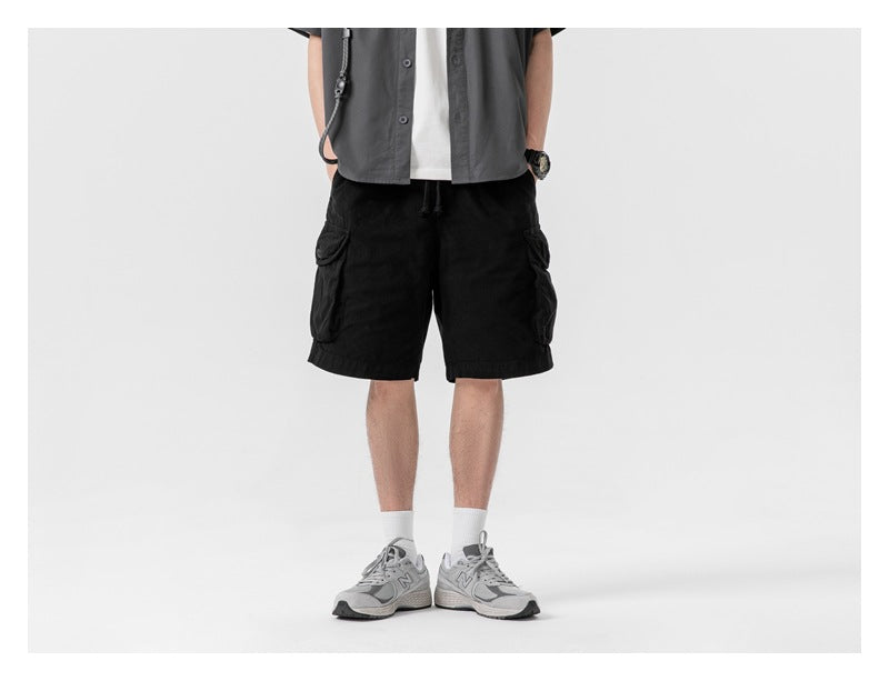 Person wearing black cargo shorts with a gray short-sleeve shirt, white socks and gray sneakers, cropped at torso