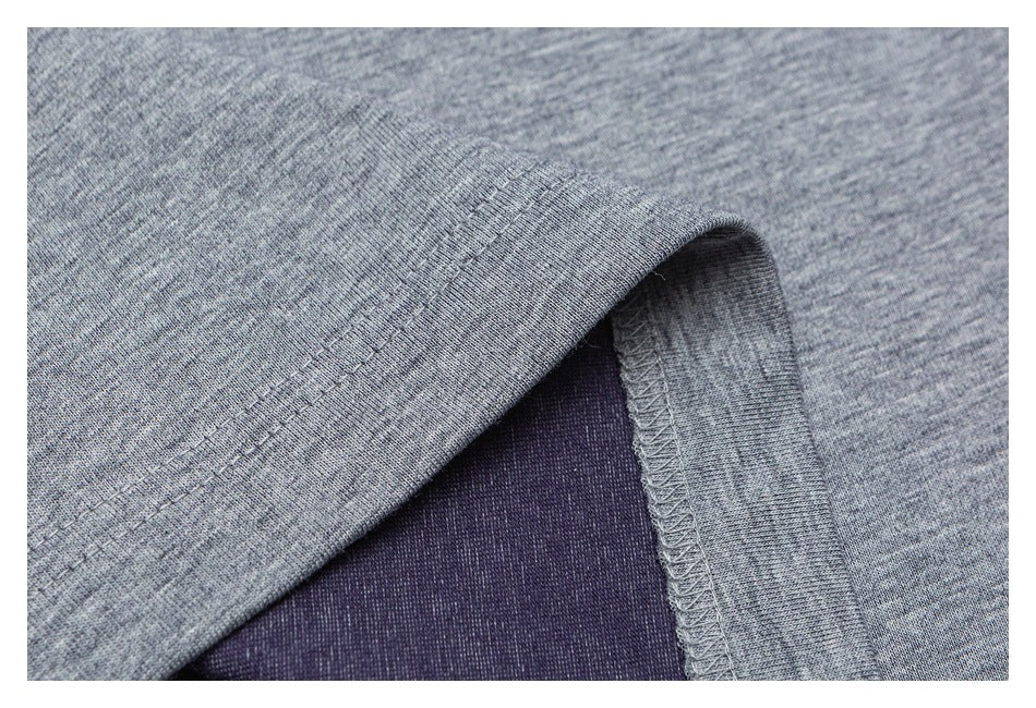 Close-up of a heather gray garment hem with visible overlock stitching and dark purple fabric underneath.