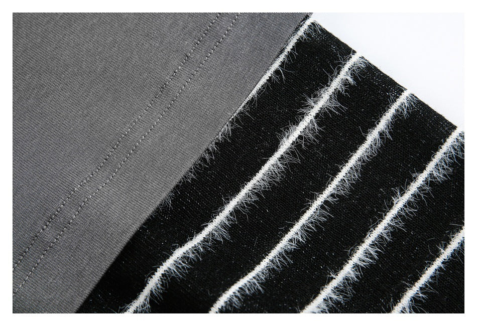 Close-up of gray fabric beside a black panel with fuzzy white stripe detailing.